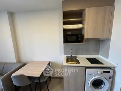 Modern compact kitchen with washing machine and dining area in a cozy apartment.