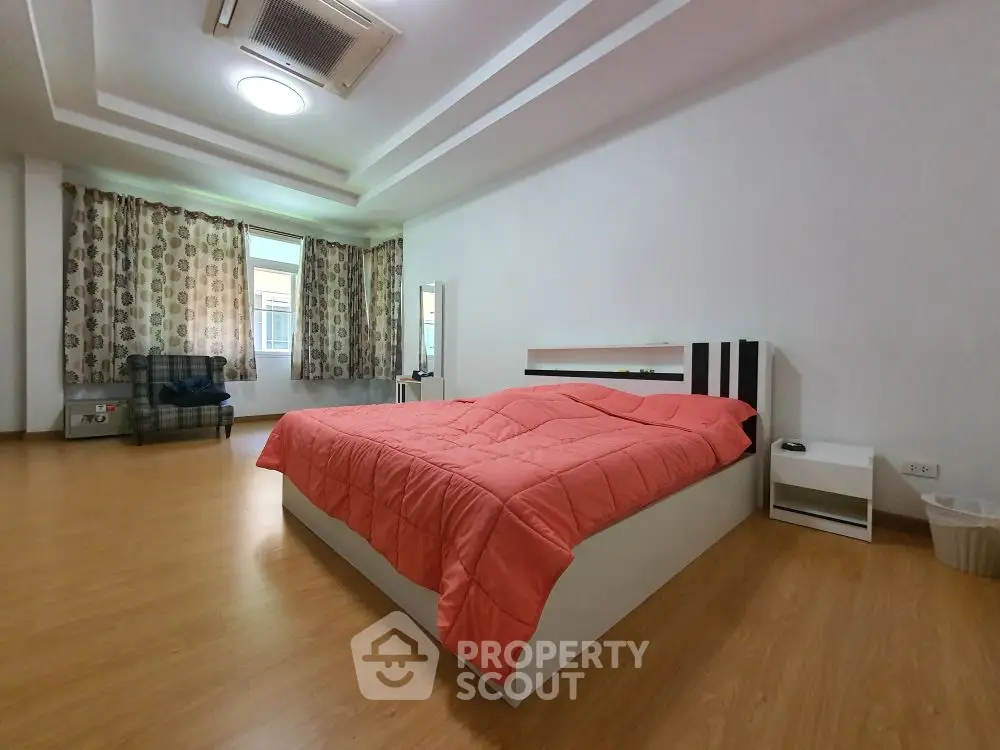Spacious bedroom with modern decor and large windows for natural light.