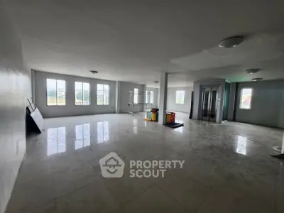 Spacious open-plan room with large windows and elevator access, ideal for versatile use.