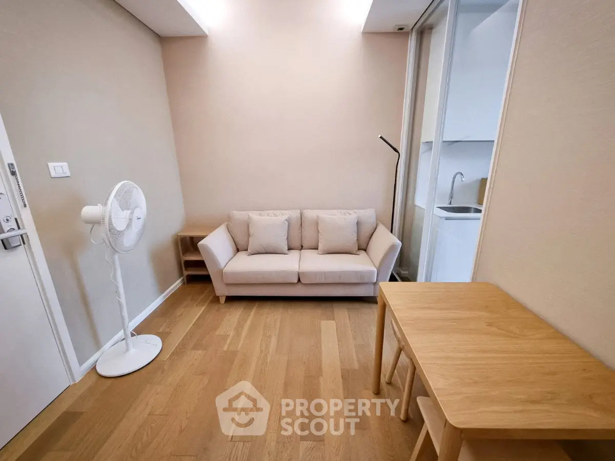 Cozy living room with modern furniture and wooden flooring, featuring a compact sofa and a sleek floor lamp.