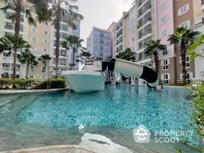 Luxurious residential complex with pool and waterslide, surrounded by palm trees and colorful buildings.