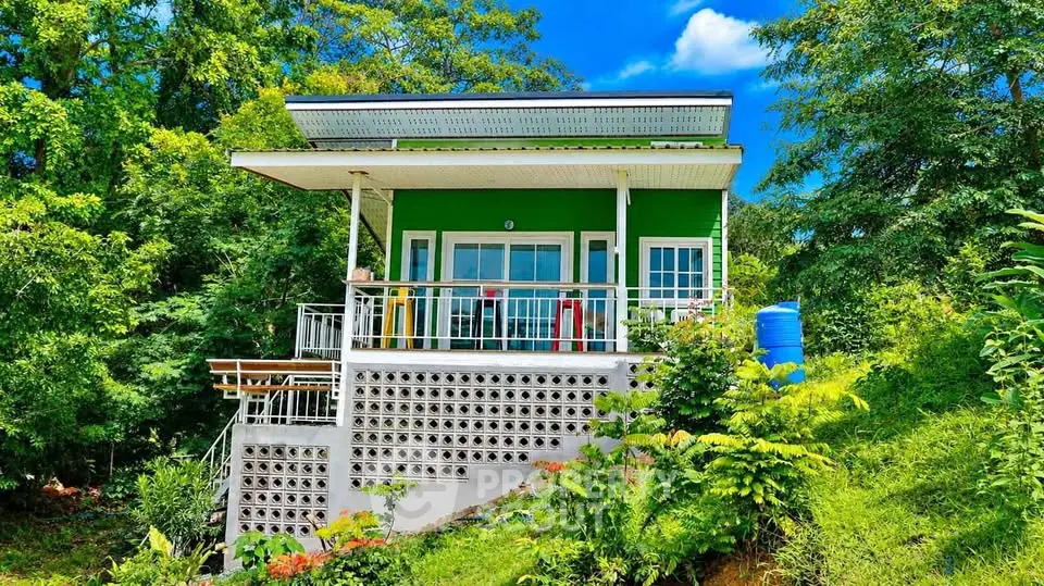 Charming green hillside house with spacious balcony and lush surroundings, perfect for nature lovers.