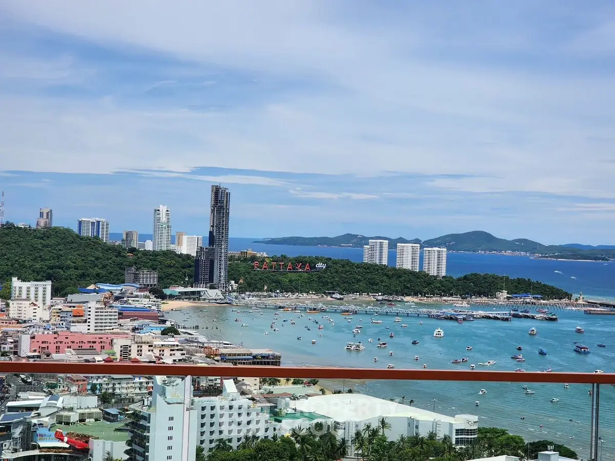 Stunning panoramic view of Pattaya city skyline and ocean from a high-rise balcony.