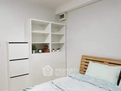 Cozy bedroom with modern white shelving and wooden bed frame, perfect for a serene living space.