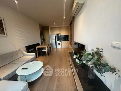 Modern living room with open kitchen, featuring stylish furniture and wooden flooring.