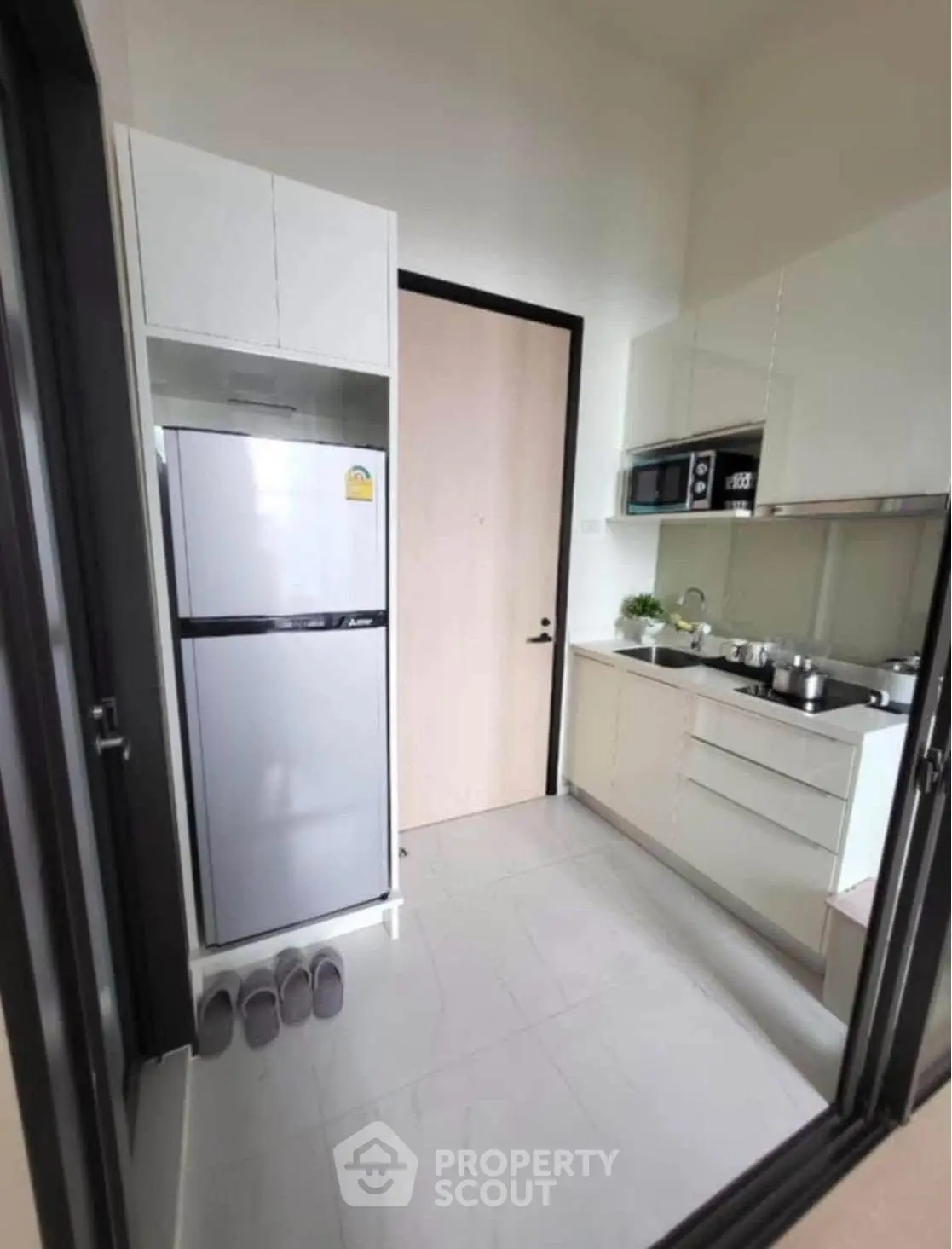 Modern kitchen with sleek appliances and minimalist design, featuring a fridge and microwave.