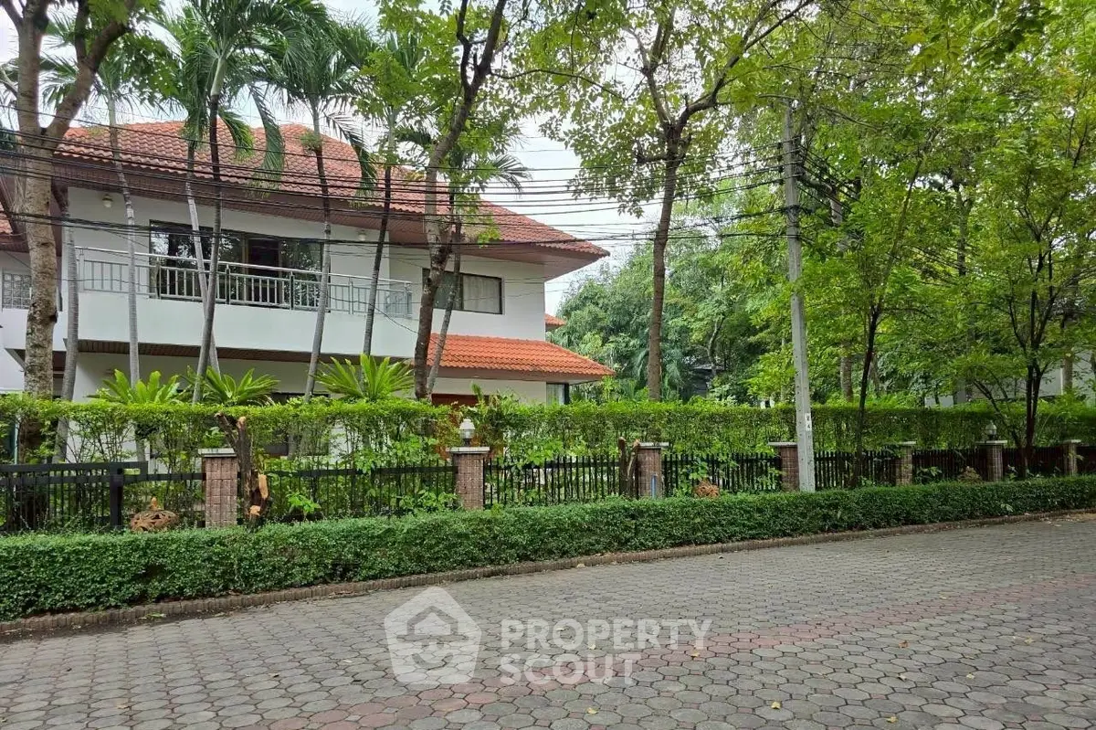 Charming two-story house with lush garden and red-tiled roof in serene neighborhood.