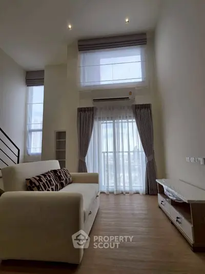 Spacious living room with high ceilings and modern decor in a stylish apartment.
