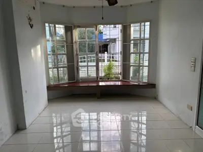 Spacious room with large windows offering abundant natural light and a serene view, perfect for a cozy living area.