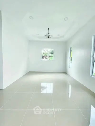 Spacious empty room with glossy tiled floor and chandelier, perfect for customization.
