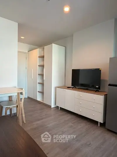 Modern living room with sleek furniture and TV, featuring a minimalist design and ample storage space.