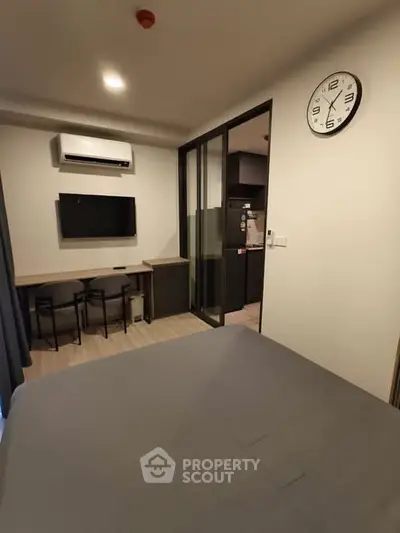 Modern bedroom with wall-mounted TV and air conditioning, featuring a sleek design and cozy atmosphere.