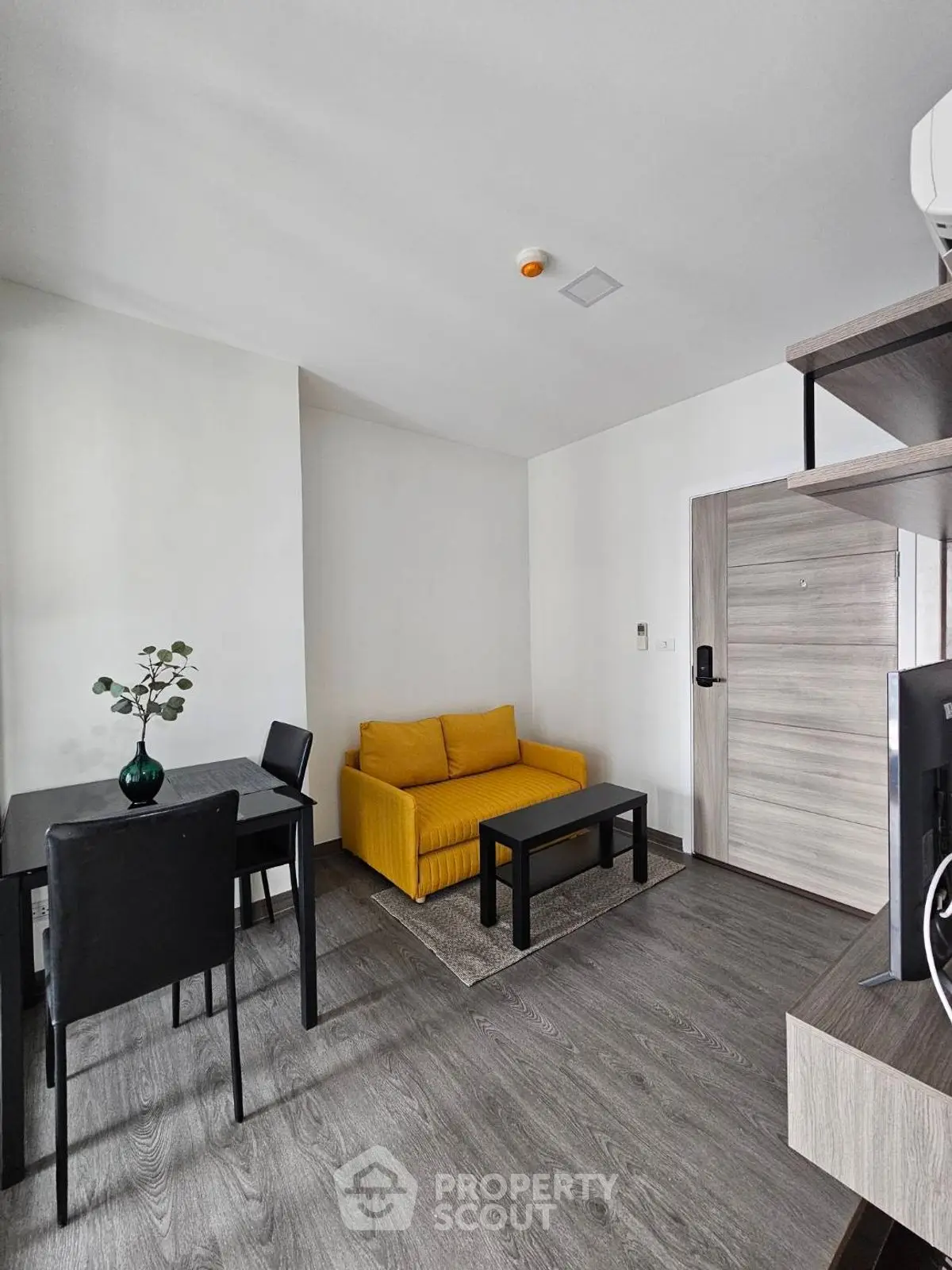 Modern living room with yellow sofa and dining area in stylish apartment.