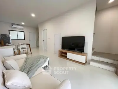 Modern living room with sleek design, featuring a cozy sofa, flat-screen TV, and dining area.