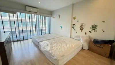 Spacious bedroom with twin mattresses and large windows in modern apartment.