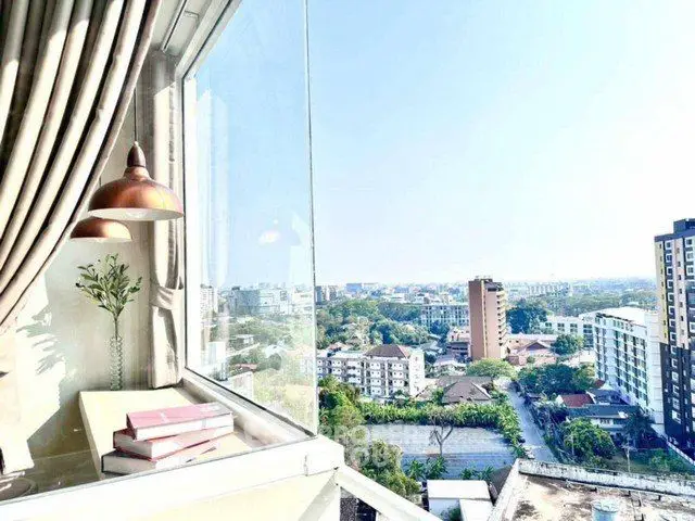Stunning high-rise view from a modern apartment window with cityscape and greenery.