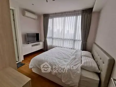 Cozy bedroom with large window and modern furnishings in a stylish apartment.