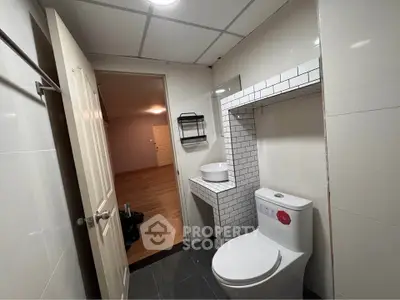 Modern bathroom with sleek fixtures and open door to adjacent room