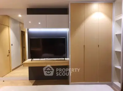 Modern bedroom with sleek TV setup and ample storage space