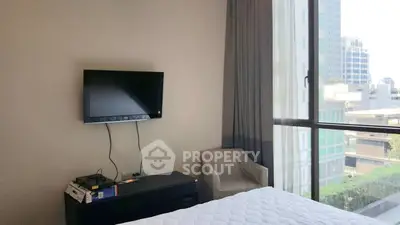 Modern bedroom with city view, wall-mounted TV, and cozy chair, perfect for urban living.