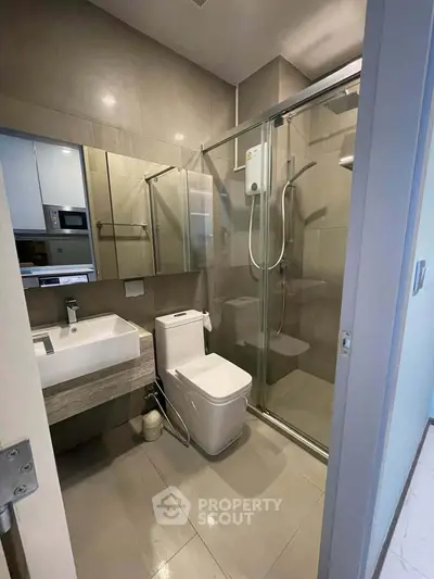 Modern bathroom with glass shower enclosure and sleek fixtures in contemporary apartment.