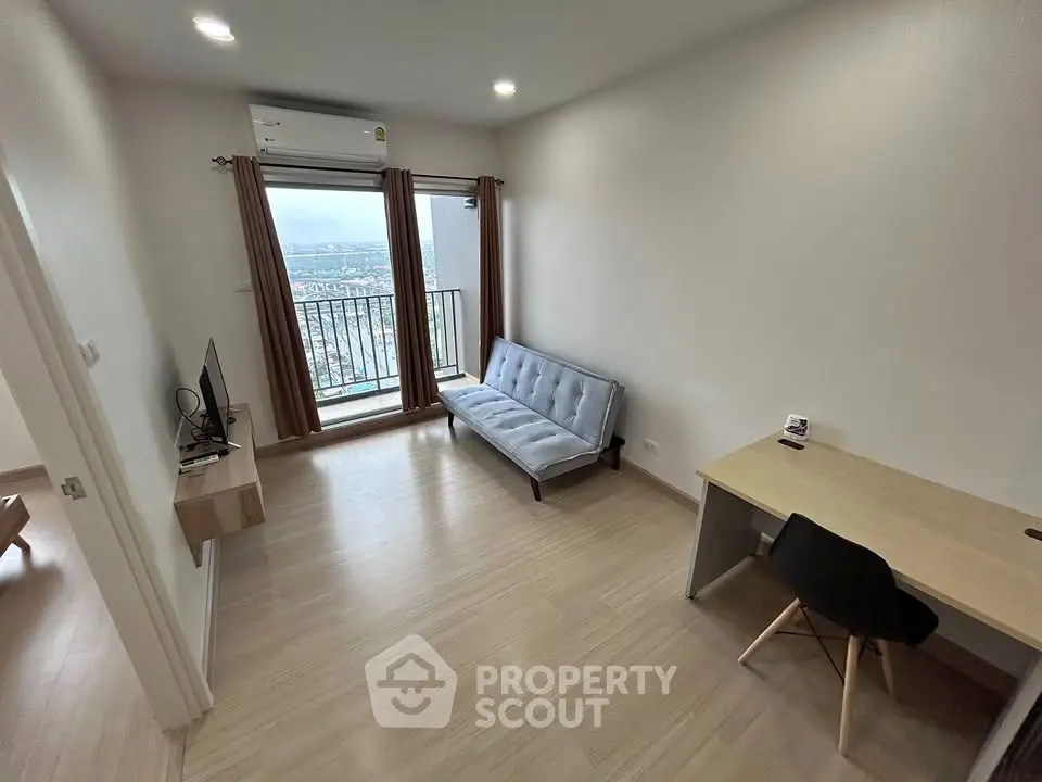 Modern living room with balcony view, featuring sleek furniture and ample natural light.