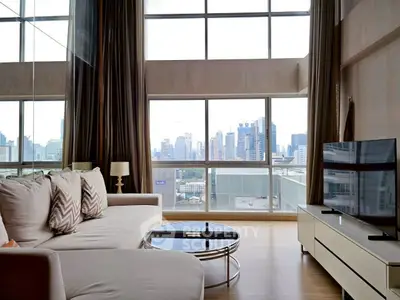 Luxurious living room with floor-to-ceiling windows offering stunning city views, modern furniture, and elegant decor.