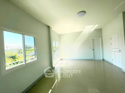 Spacious sunlit room with large windows and glossy tiled floors, perfect for modern living.