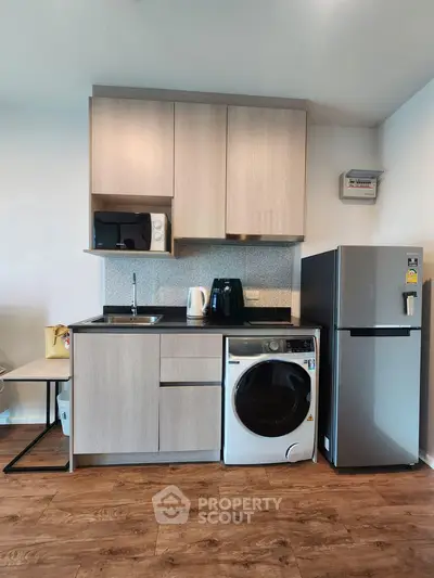 Modern compact kitchen with appliances including fridge, microwave, and washing machine in stylish apartment.