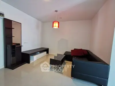 Modern living room with sleek black furniture and stylish red accents.
