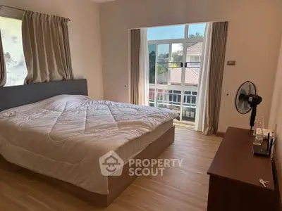 Spacious bedroom with large window and modern furnishings, offering natural light and a cozy atmosphere.
