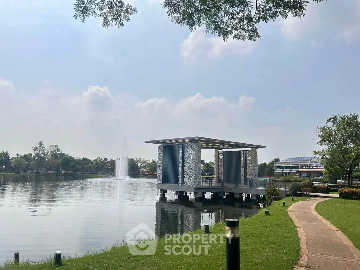 Scenic lakeside view with modern pavilion and lush greenery, perfect for tranquil living.