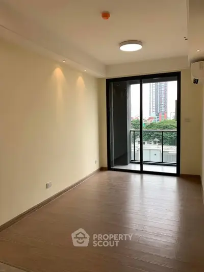 Spacious living room with large windows and balcony offering city views in modern apartment.