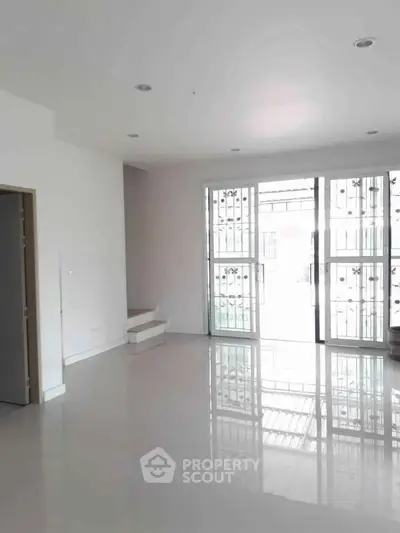 Spacious empty living room with large windows and glossy floor