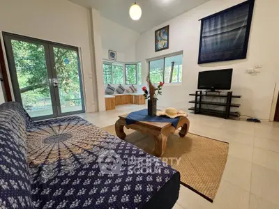 Charming living room with cozy decor and lush garden view, perfect for relaxation and entertainment.
