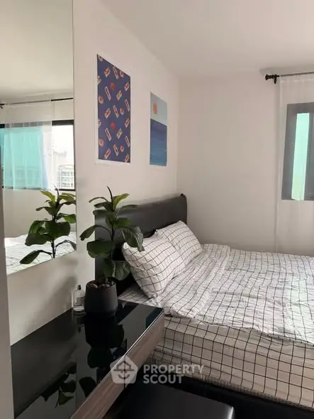 Cozy bedroom with modern decor and large mirror reflecting natural light.