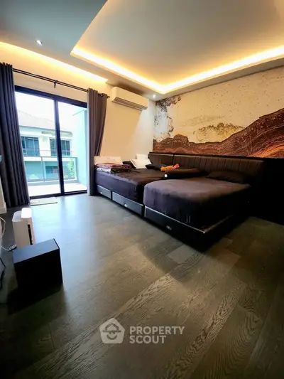 Spacious modern bedroom with large windows and stylish decor, featuring a cozy bed and elegant lighting.
