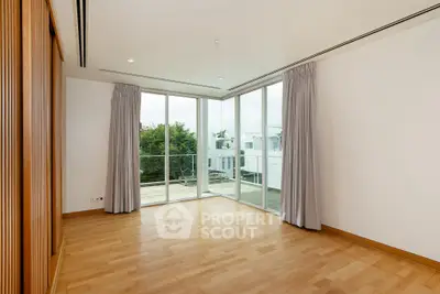 Spacious empty room with large windows and wooden flooring, offering a bright and airy atmosphere.