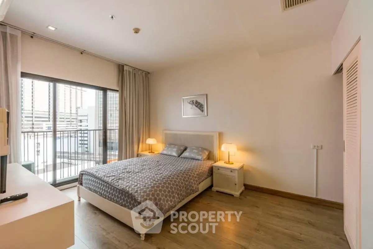 Spacious bedroom with balcony access in modern apartment, featuring elegant decor and natural light.