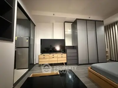 Modern bedroom with sleek furniture and large TV, perfect for urban living.