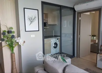 Modern apartment interior with cozy living room and compact kitchen featuring a washing machine.