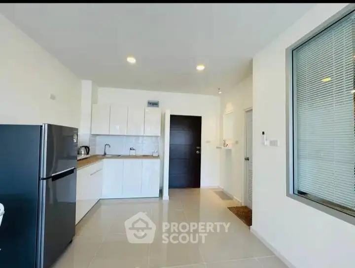 Modern kitchen with sleek white cabinets and stainless steel fridge in a bright apartment.