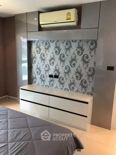 Modern bedroom with stylish wallpaper and sleek built-in storage under air conditioning unit.