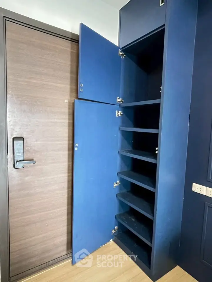 Modern blue storage cabinet with open shelves next to a wooden door in a stylish interior.