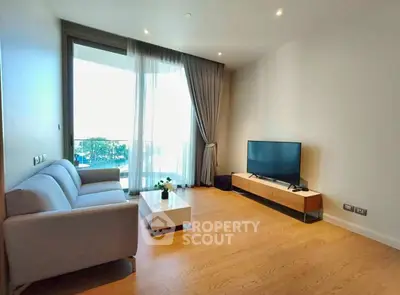 Modern living room with large window and balcony view, featuring sleek furniture and wooden flooring.