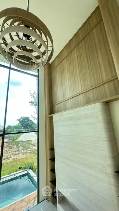 Stunning modern interior with high ceilings and large windows overlooking a serene outdoor pool area.