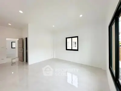 Spacious minimalist living room with large windows and bright white walls