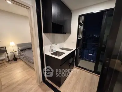 Modern compact kitchen with sleek black cabinetry and city view balcony access.