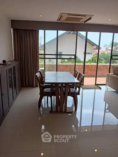Spacious dining area with large windows and balcony view in modern home.