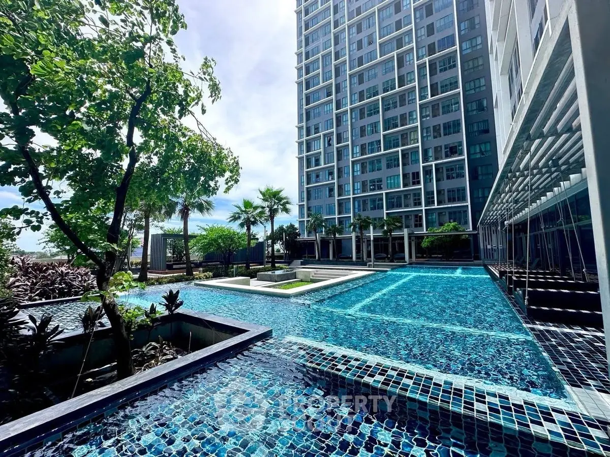 Luxurious high-rise building with stunning pool and lush greenery, perfect for modern living.